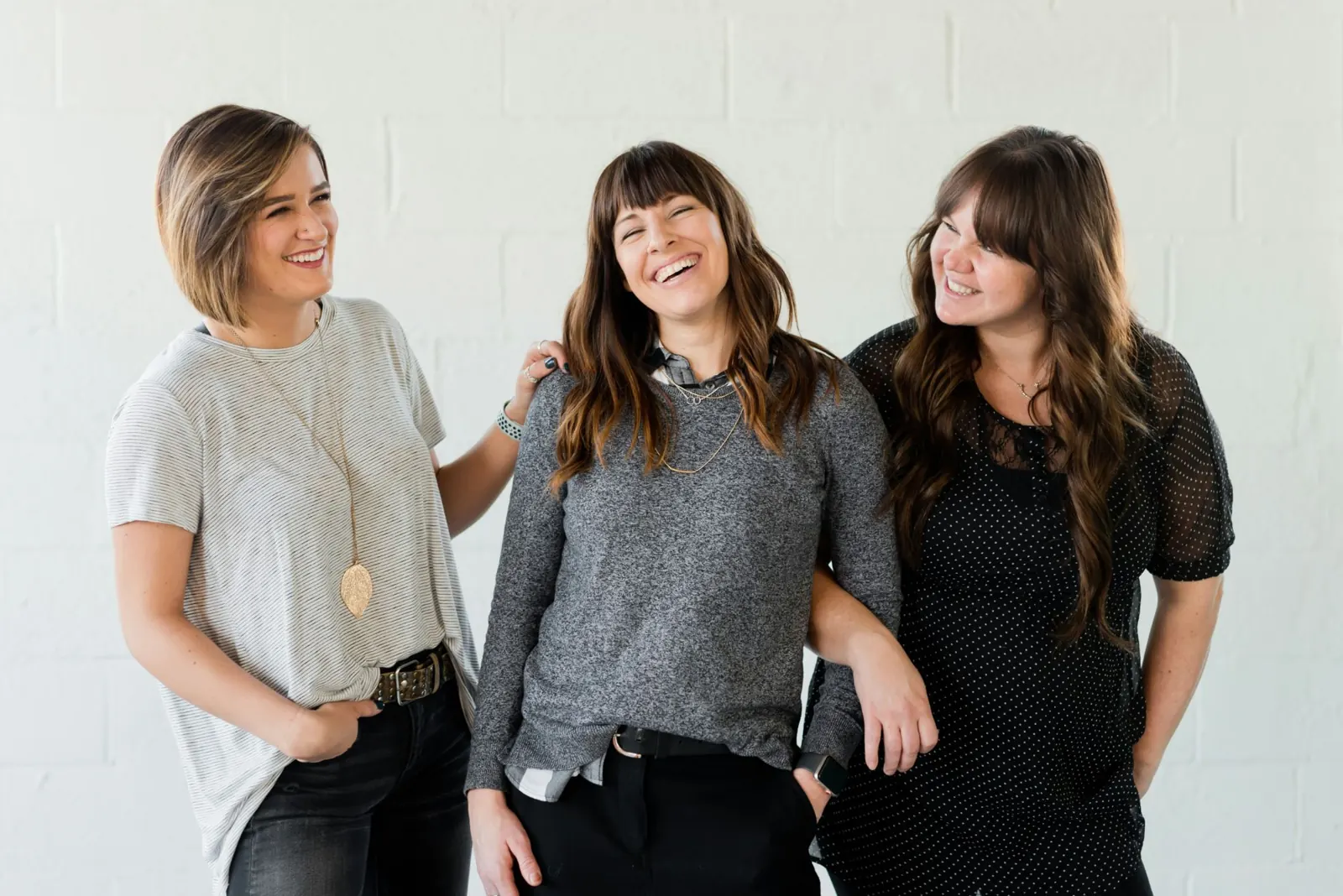 Three women laughing together, arms around one another