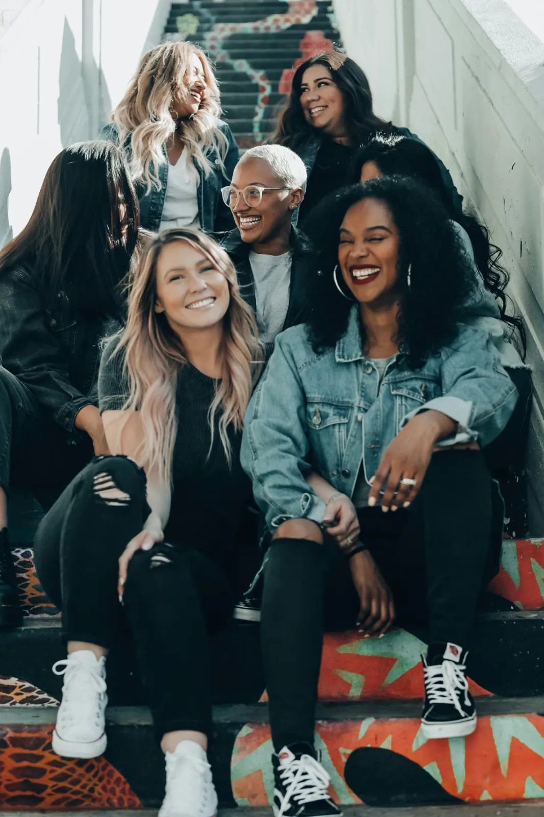 A group of women sitting together on a painted staircase, laughing